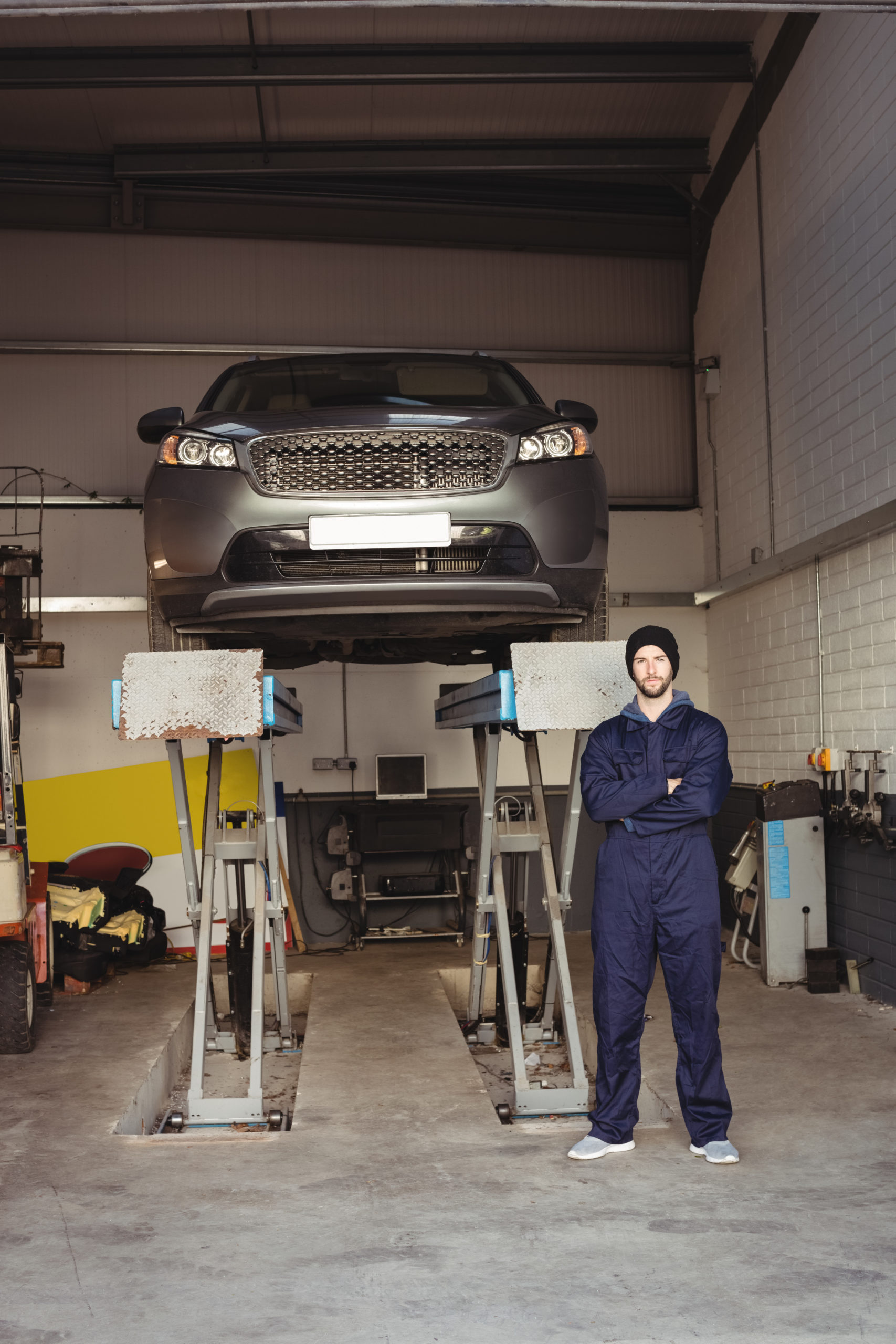 Portrait of mechanic standing with arms crossed in repair garage